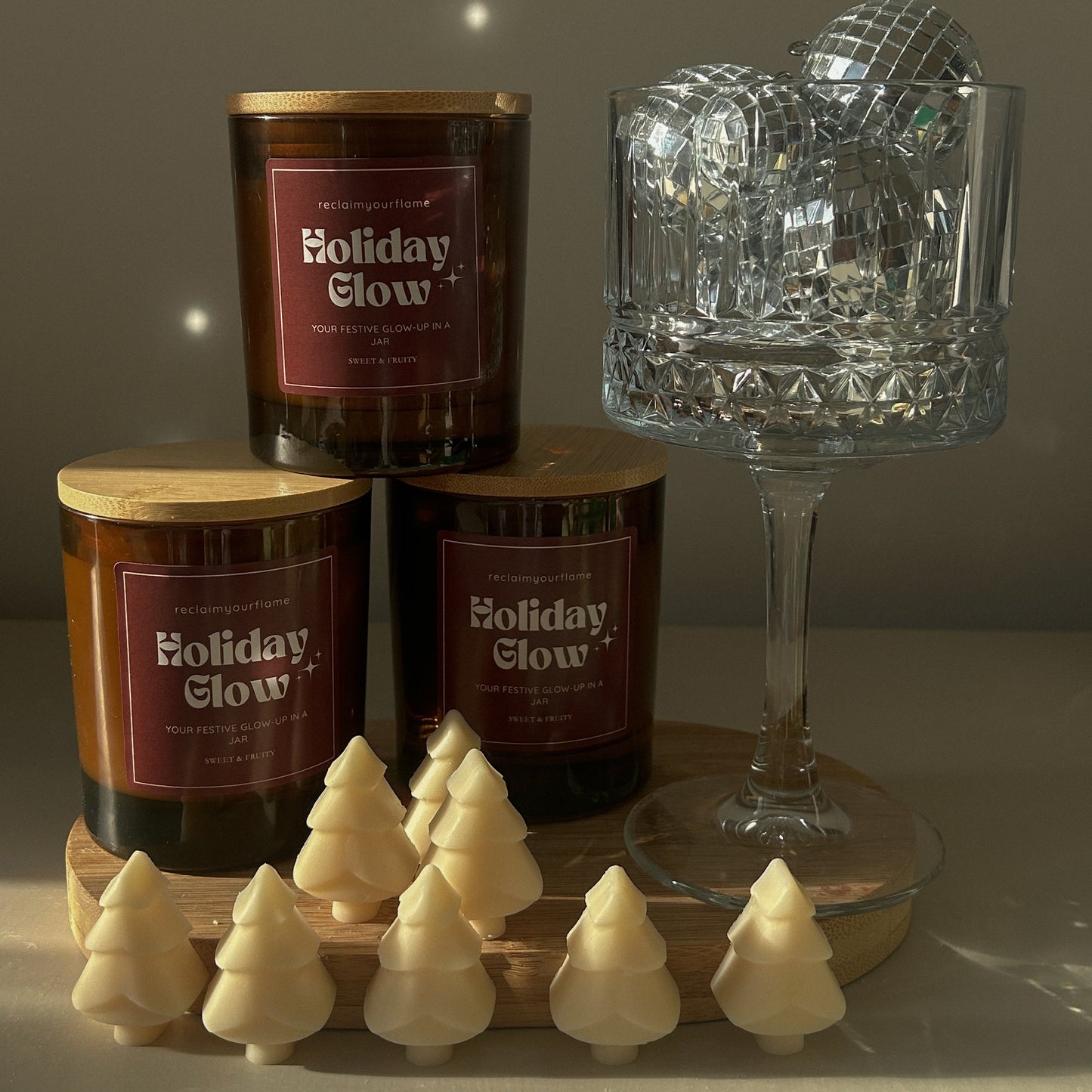 Candle labeled 'Holiday Glow' with decorative items on a neutral background