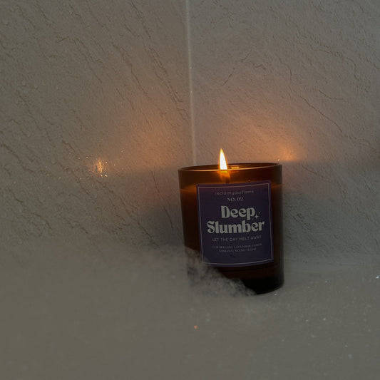 Candle labeled 'Deep Slumber' on a white wall in a bubble bath environment