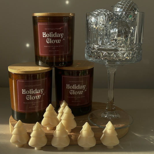 Candle labeled 'Holiday Glow' with decorative items on a neutral background